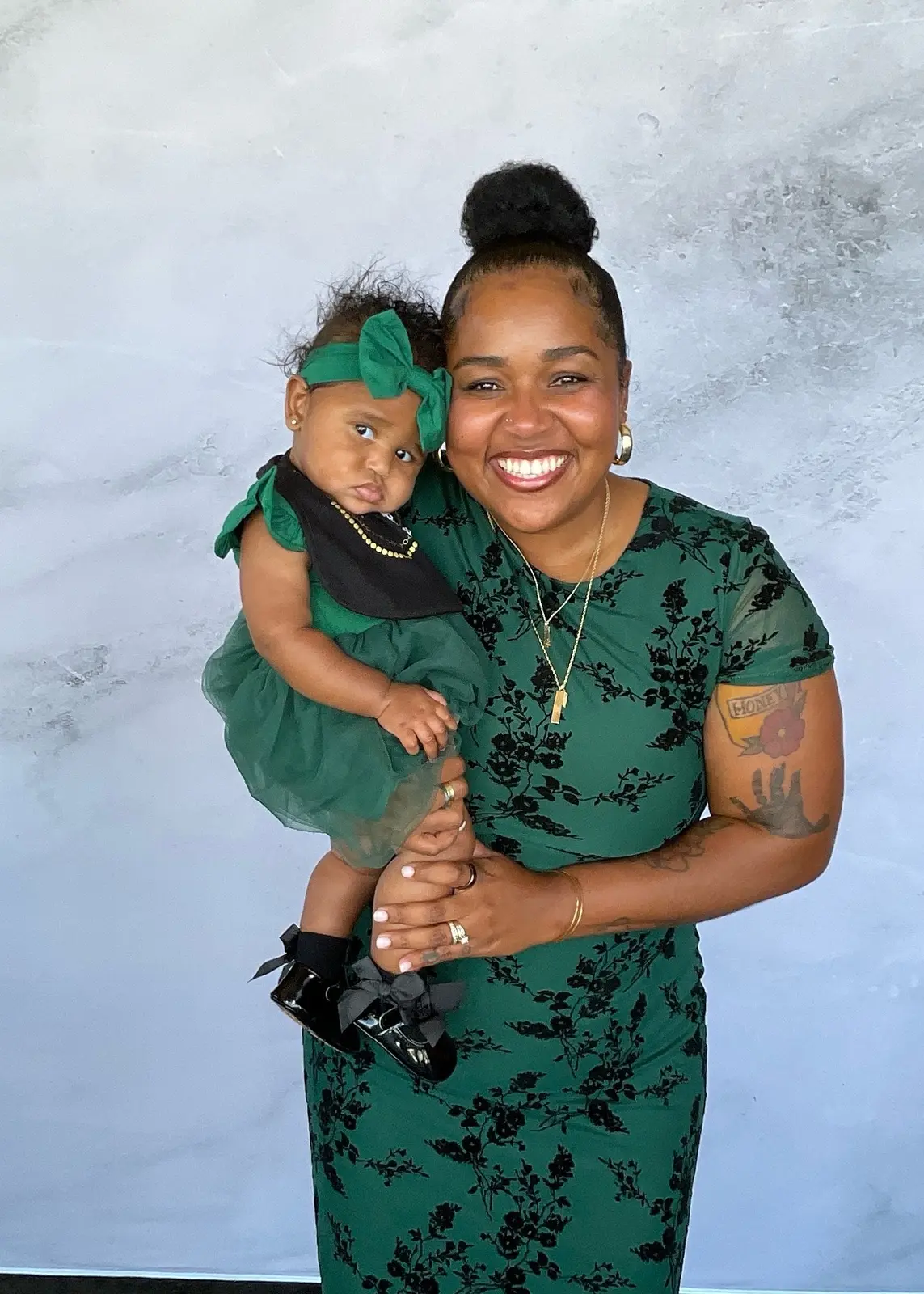 Smiling woman holding a baby in matching emerald green outfits