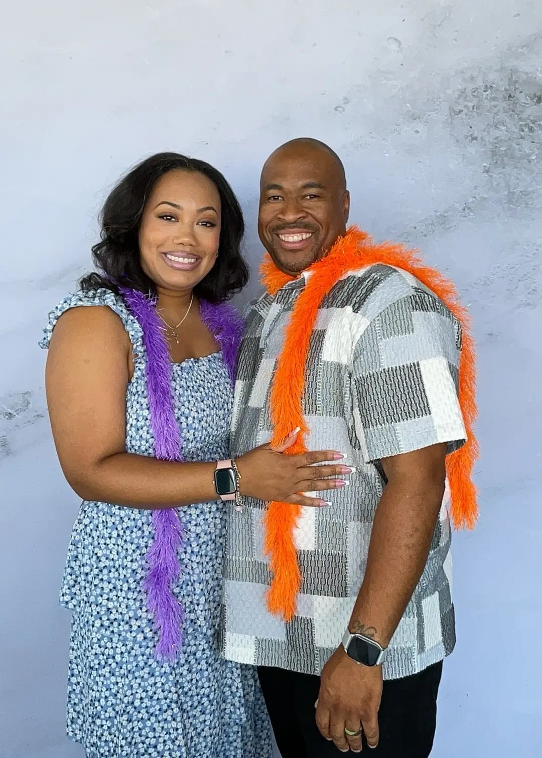 Couple smiling in purple and orange feather boas