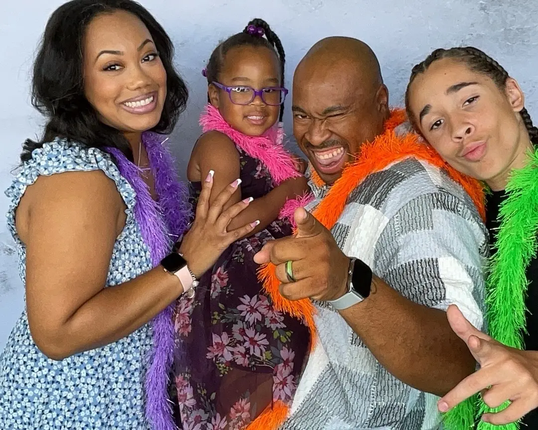 Family sharing a lively photo booth pose with colorful feather boas