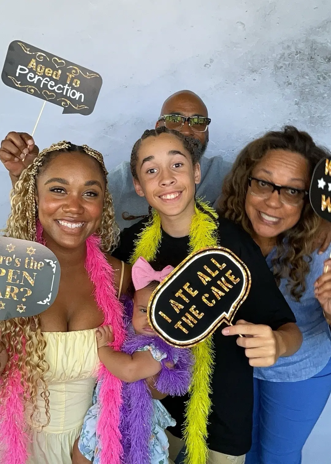 Family crowding into the photo booth with fun party props