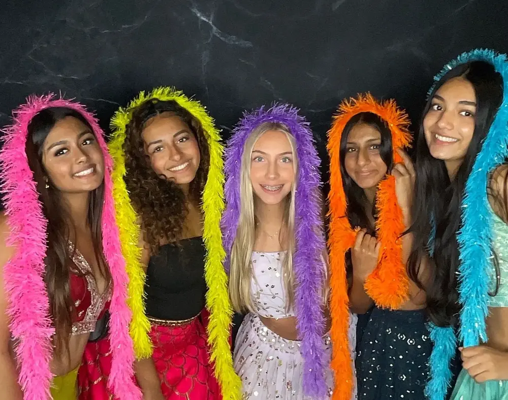 Party guests posing with colorful feather boas