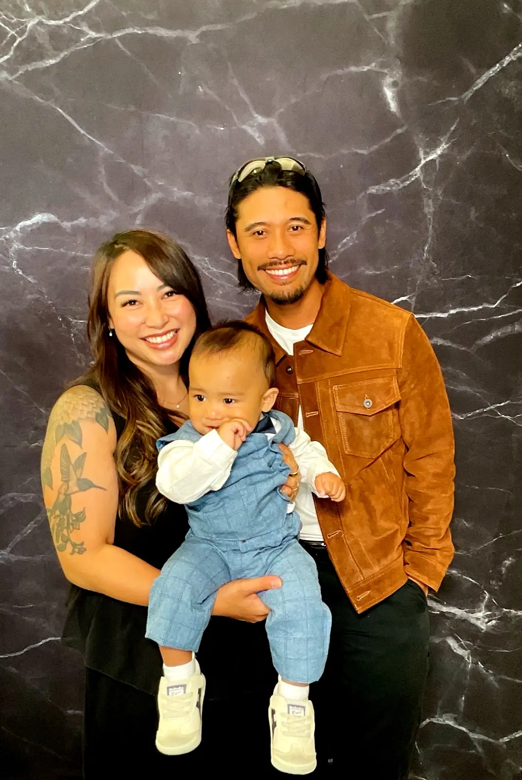 Smiling couple holding a baby in the retirement party photo booth