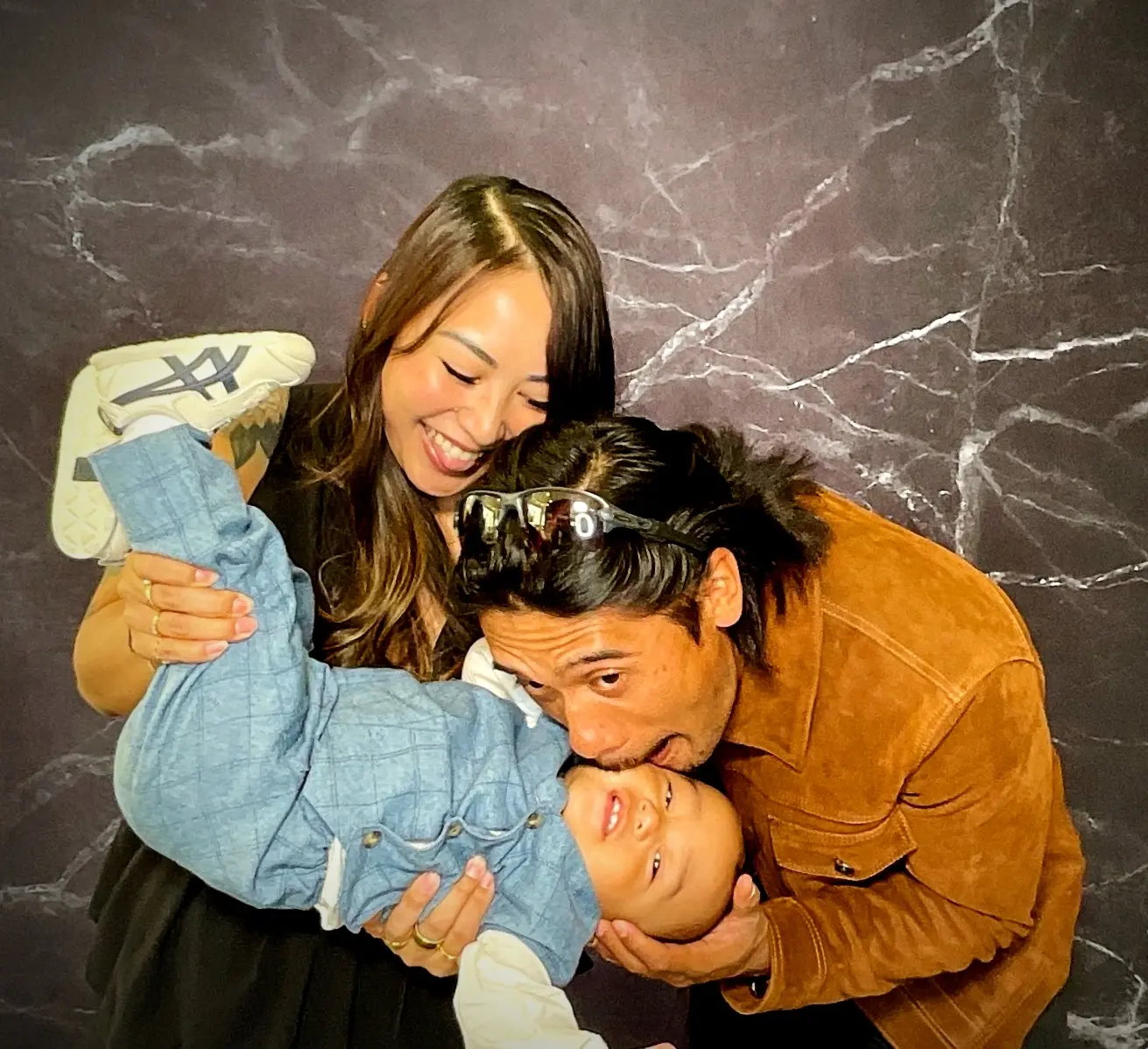 Parents sharing a playful photo booth moment with their baby