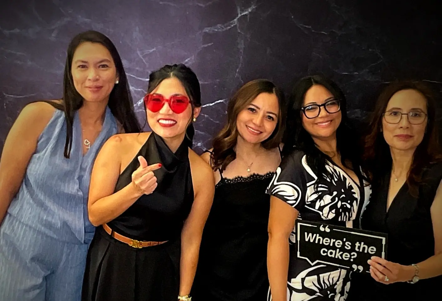 Five guests smiling with a Where's the cake photo booth sign