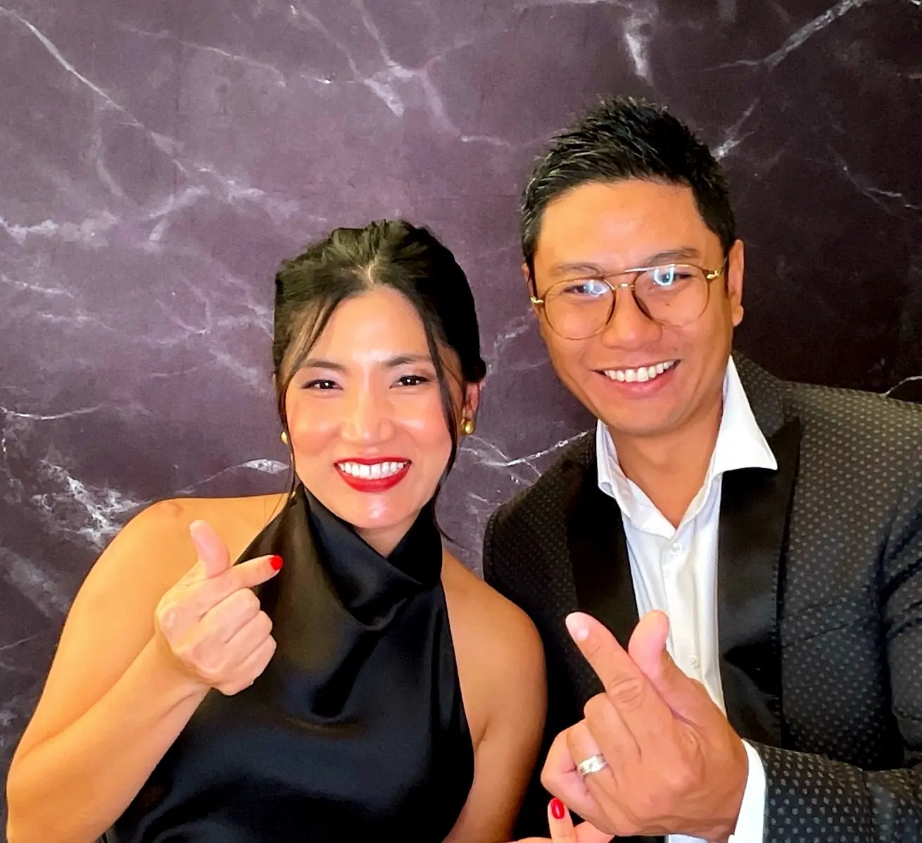 Two retirement party guests making finger-heart poses for the camera