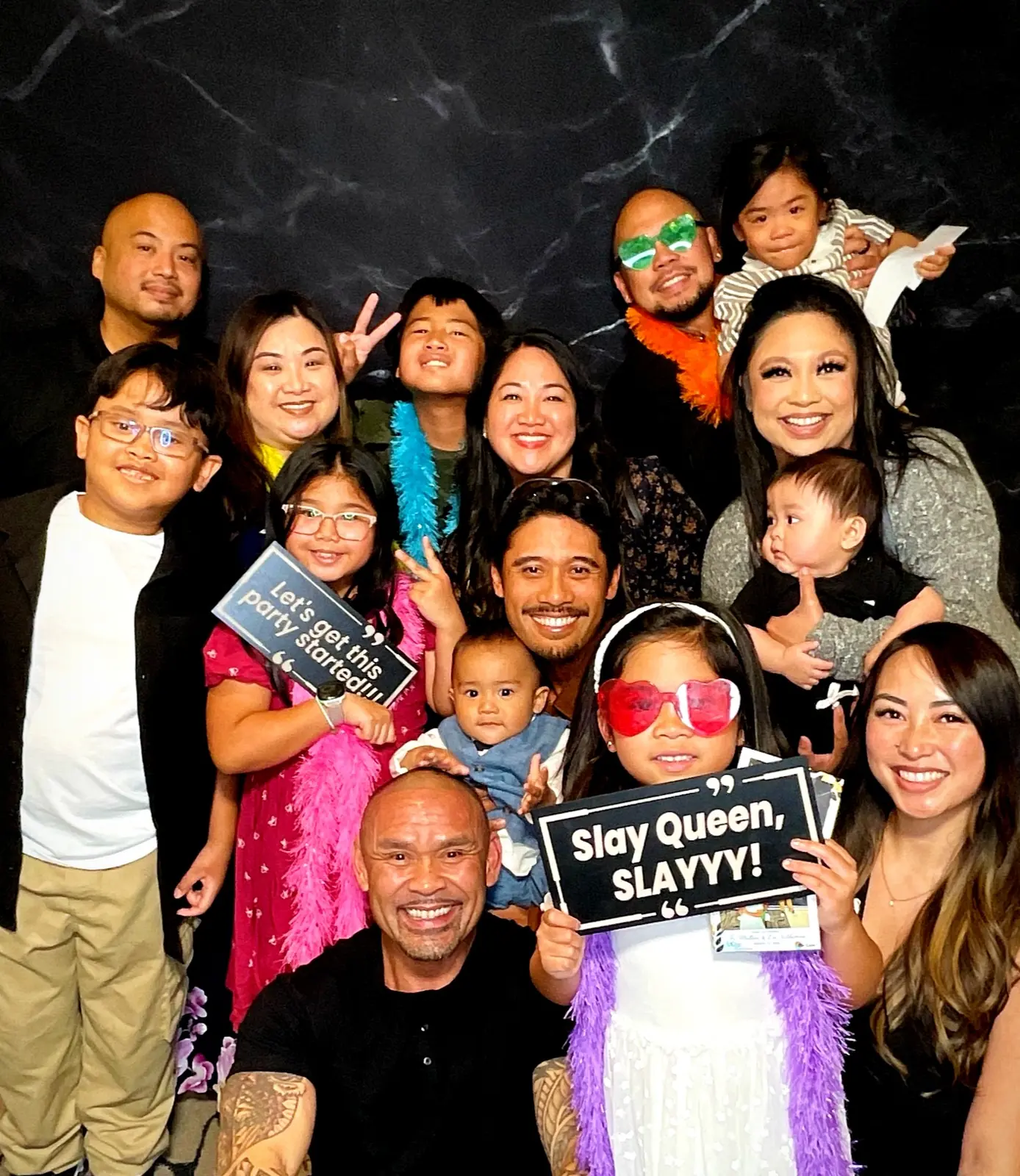 Large family group celebrating together with colorful photo booth props