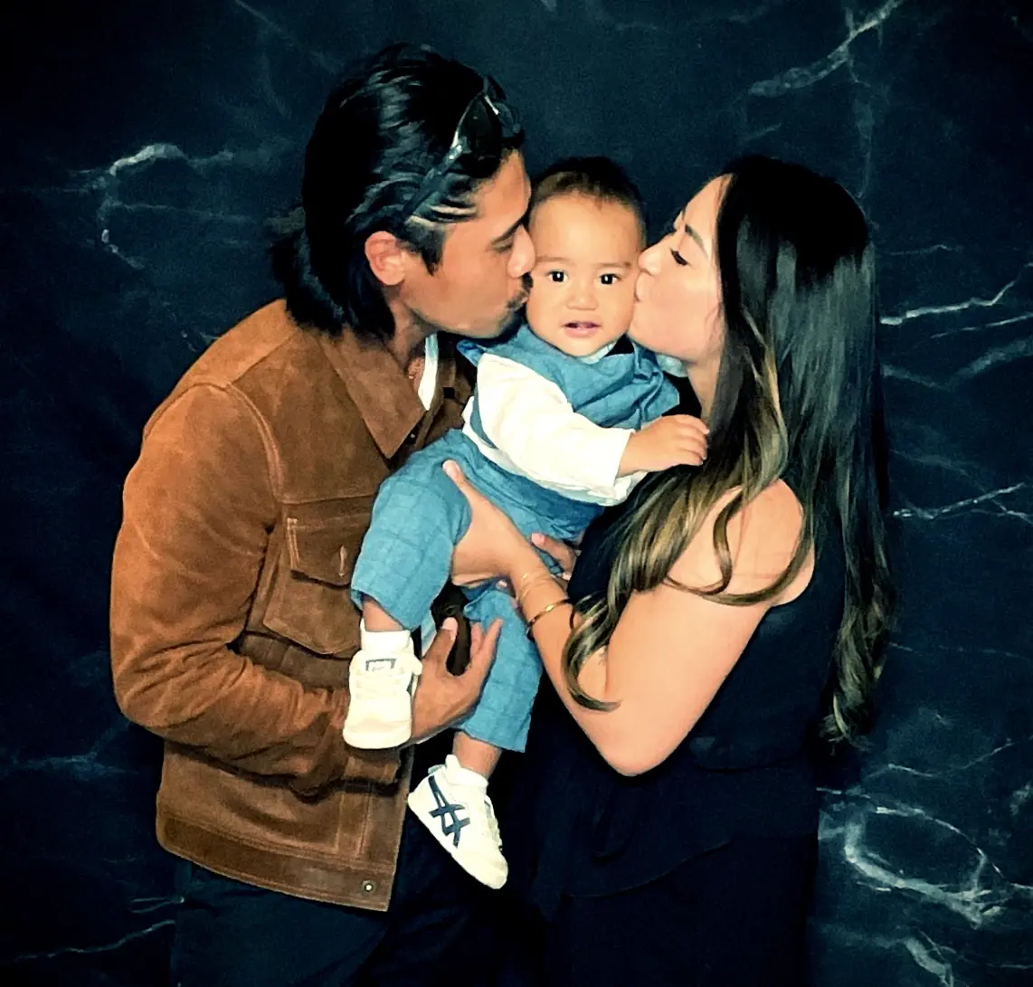 Parents kissing their baby during a joyful retirement party photo booth moment