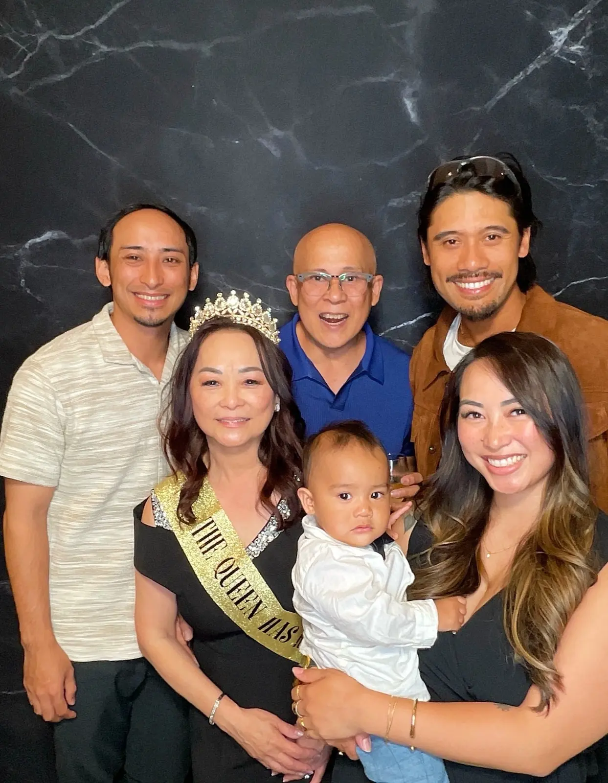 Friends and family posing with the retirement guest of honor and a young child