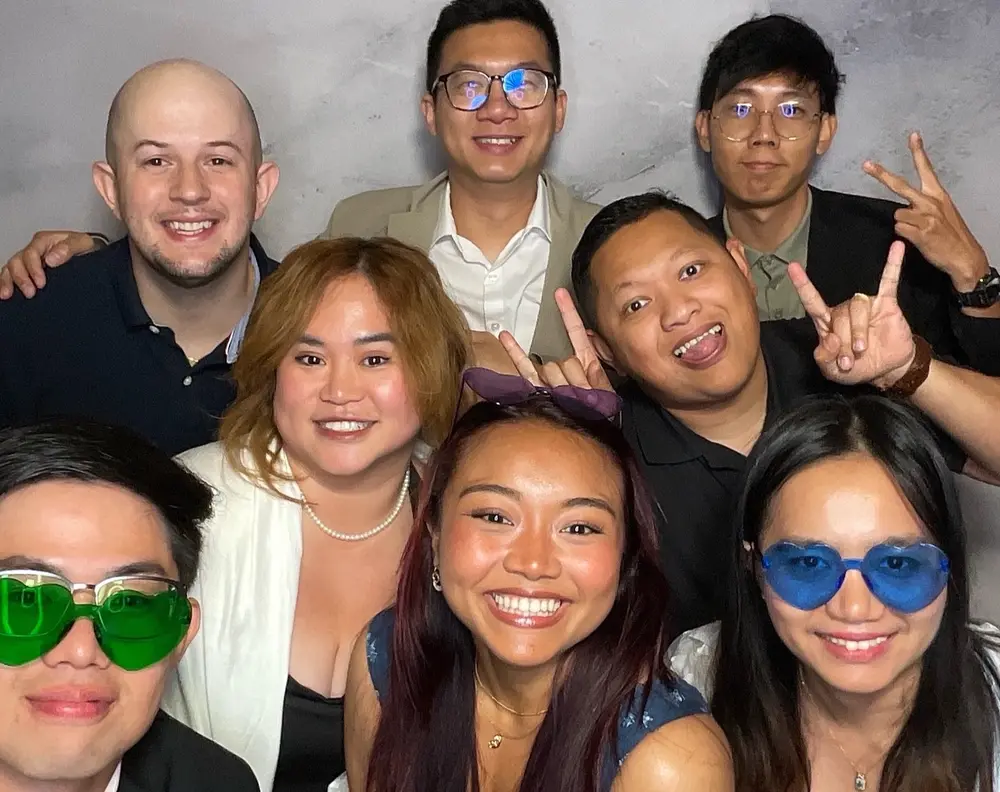 Six friends smiling together in a lively wedding photo booth moment