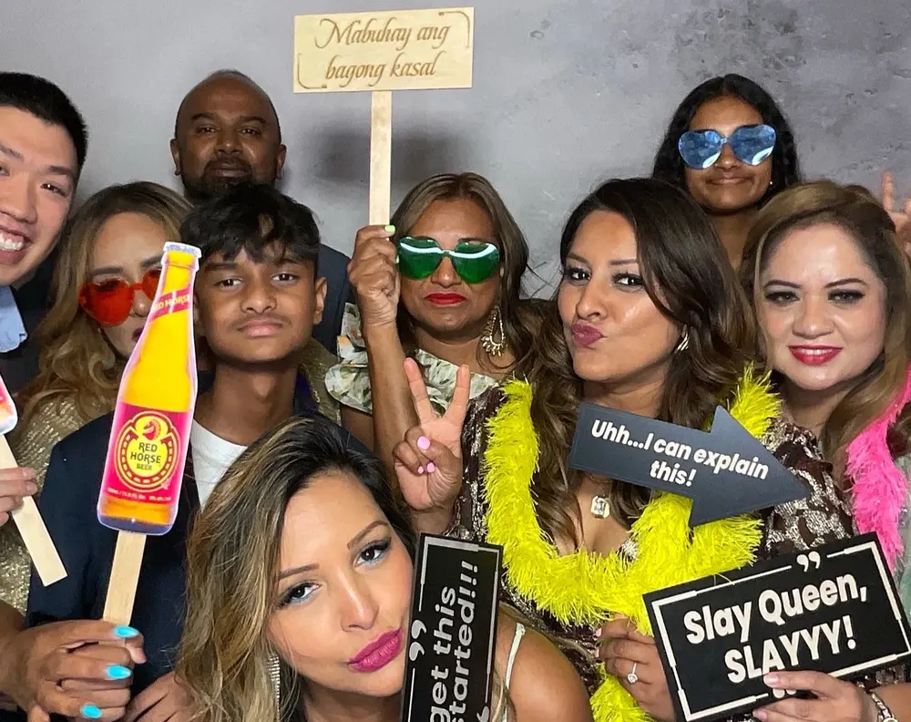 Large wedding group posing with colorful glasses and humorous party signs