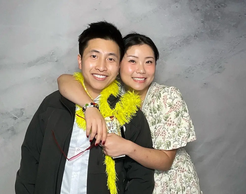 Wedding couple smiling together while wearing a bright yellow feather boa