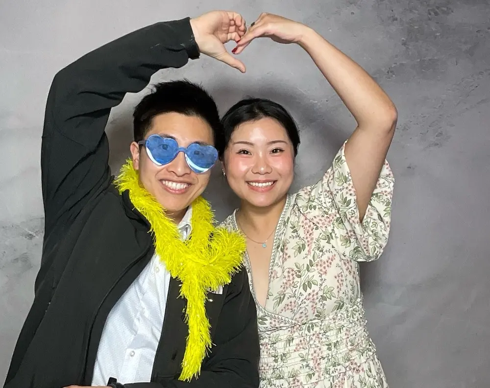 Wedding couple making a heart above their heads in the photo booth