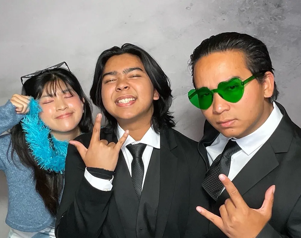Three wedding guests wearing sunglasses and a blue feather boa