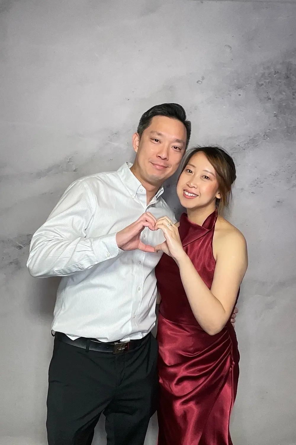 Wedding guests sharing a playful heart pose against a marble backdrop