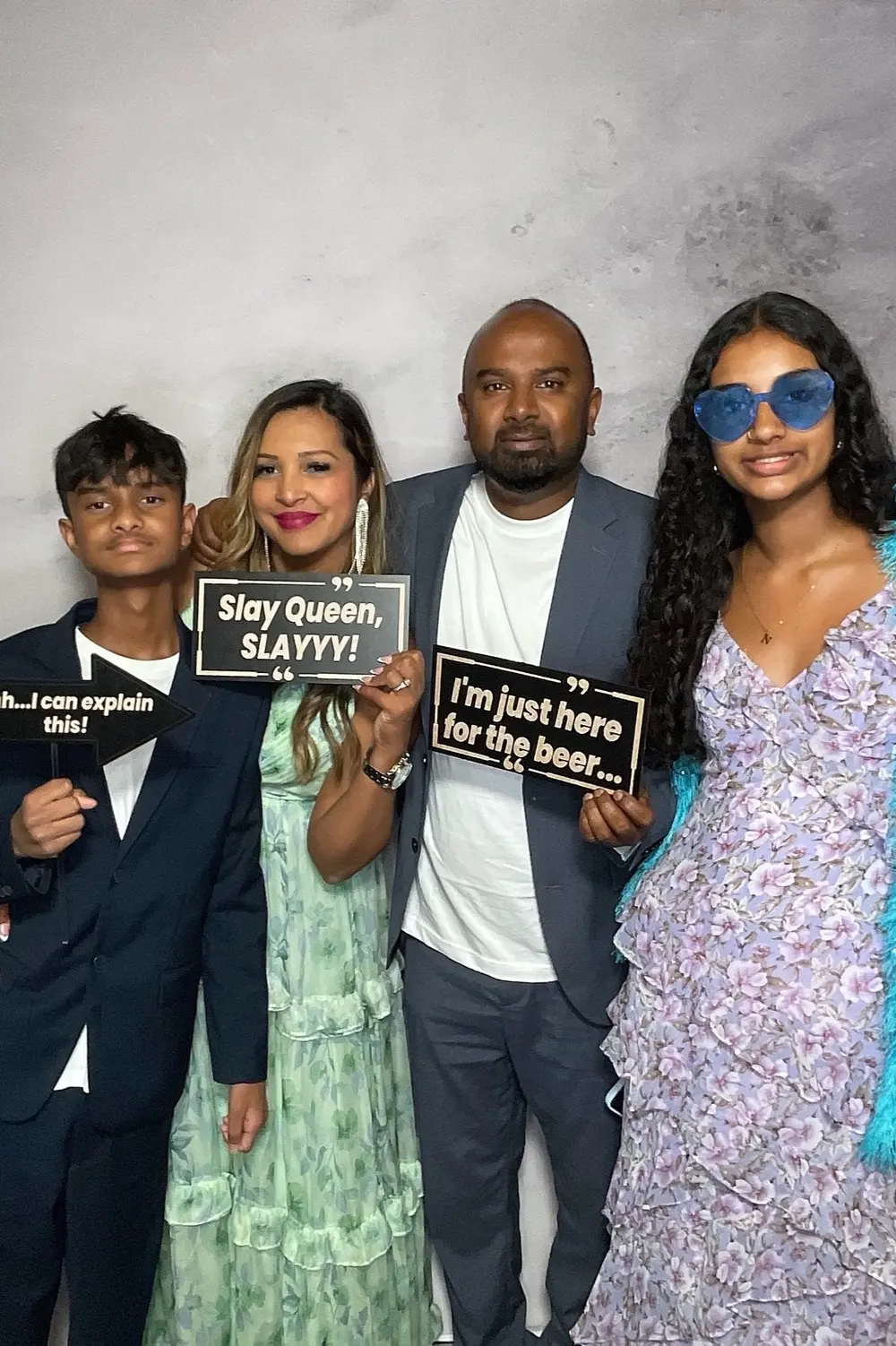 Family group posing with wedding reception signs and blue sunglasses