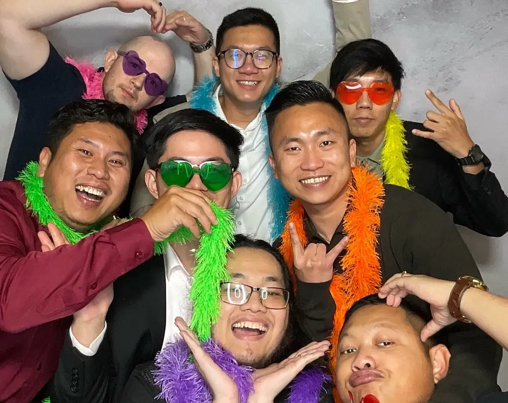 Large group of wedding guests celebrating with bright feather boas