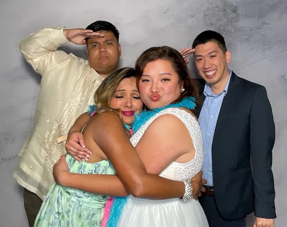 Bride embraced by three friends during a joyful photo booth moment
