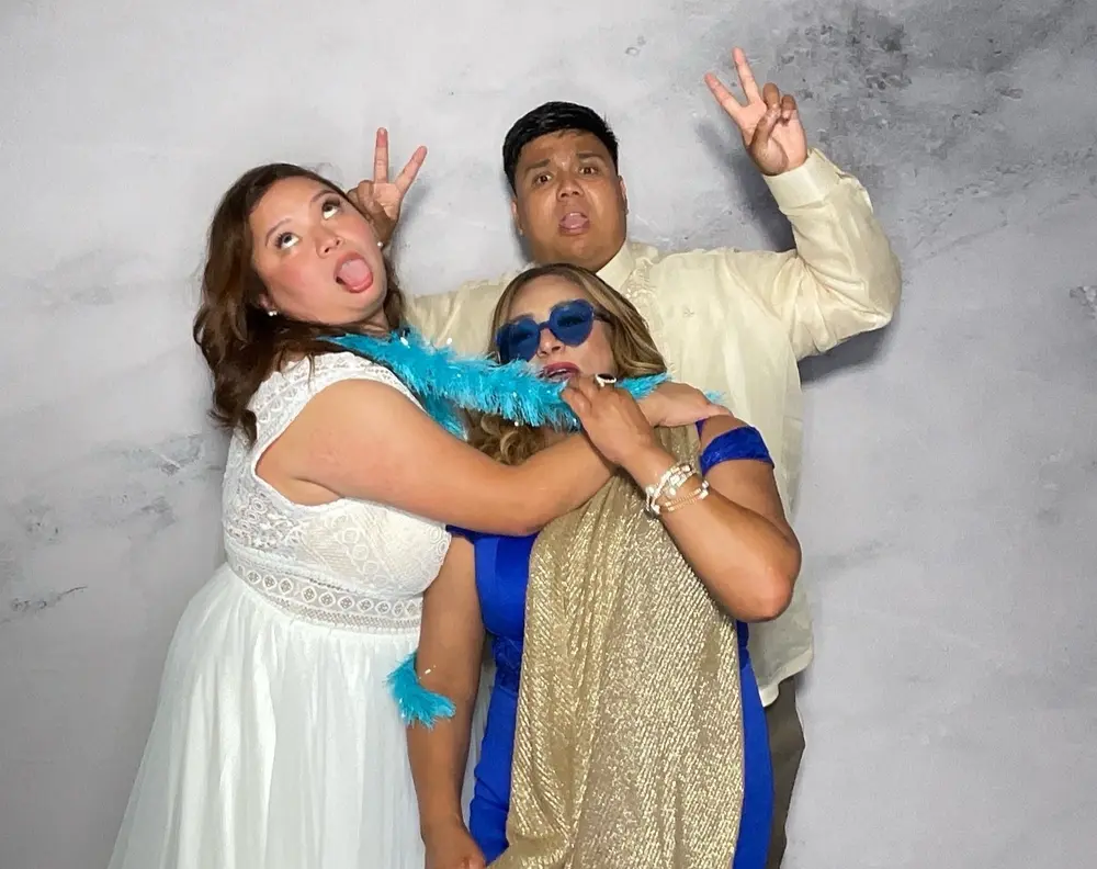 Bride and two friends laughing together with a blue feather boa